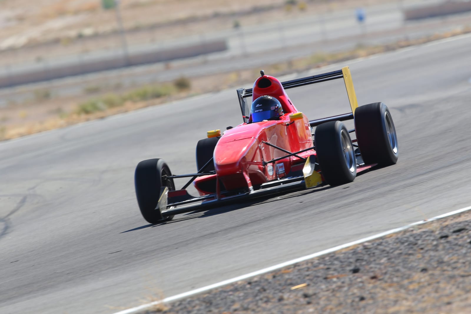 A FastLane Ligier JS F4 open-wheel formula car at speed on Buttonwillow Raceway.