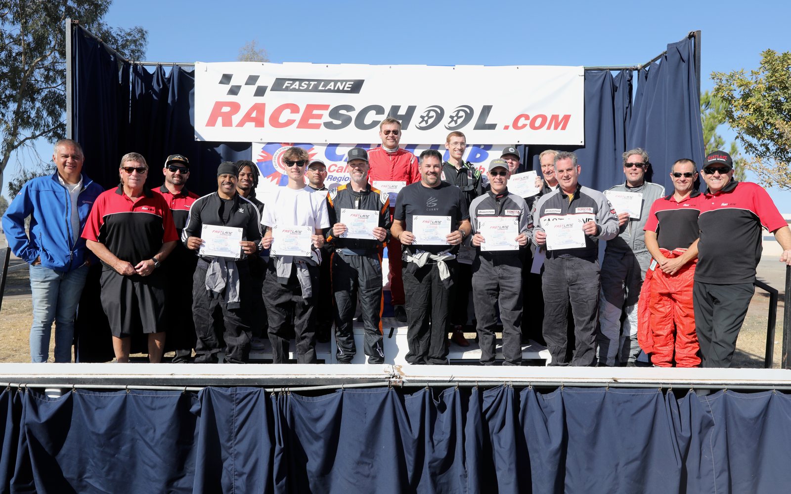 A FastLane corporate and team group on stage with their certificates at Buttonwillow Raceway Park.