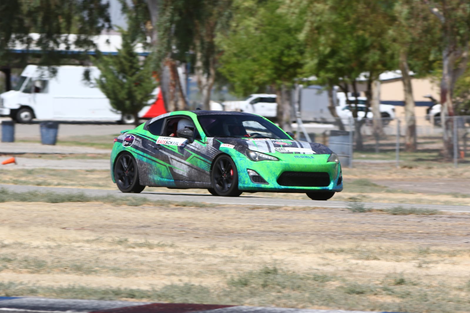 A liveried sports car hard through a corner at Buttonwillow Raceway Park.