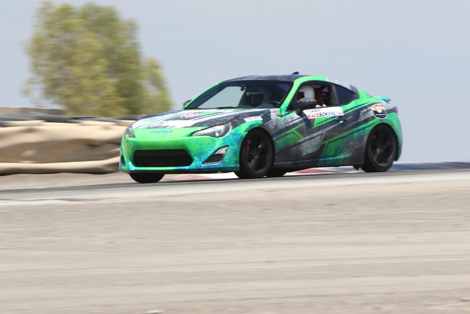 A RaceSchool.com-liveried car carrying speed through a sweeper at Buttonwillow Raceway Park.