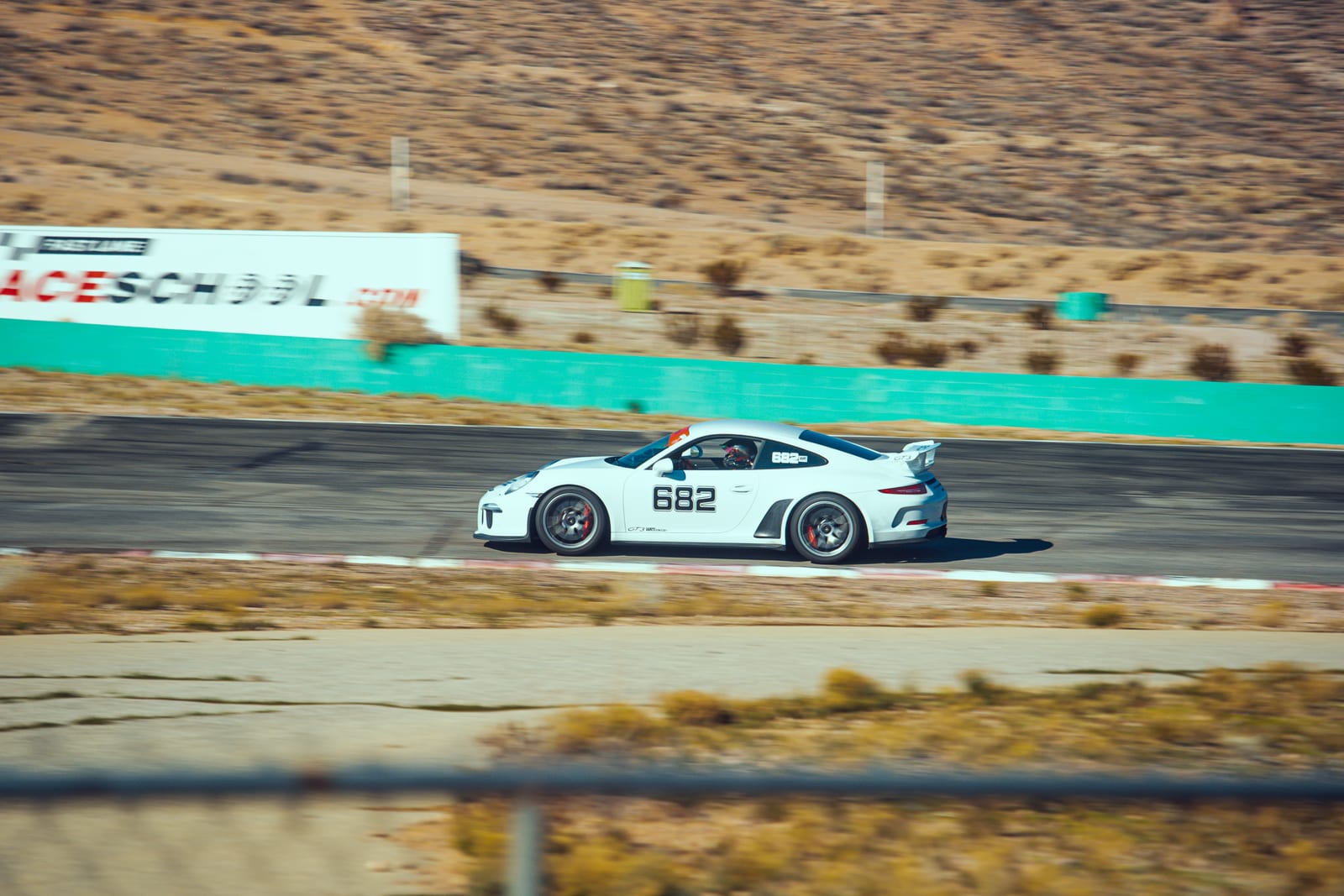 A wide track shot of a sports car at speed at Buttonwillow Raceway Park.