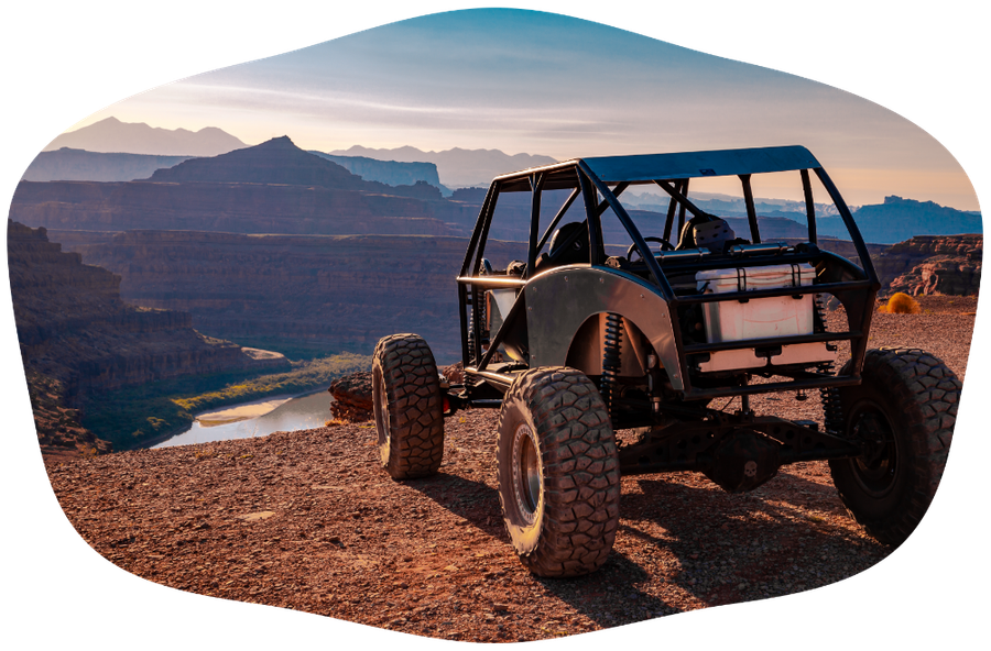 An off-road vehicle on a desert ridge at sunset